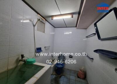 Bathroom with tiled walls, basin, shower, and toilet