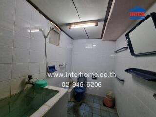 Bathroom with tiled walls, basin, shower, and toilet