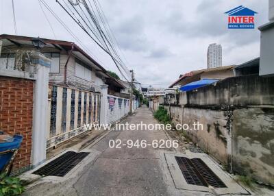 Narrow alley view with residential houses and visible contact information