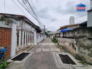 Narrow alley view with residential houses and visible contact information