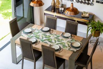 Dining room with a wooden table set for six people and a sideboard with decorative items