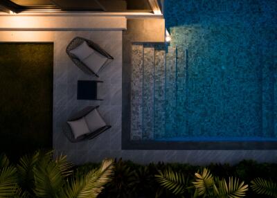 Night view of outdoor seating area next to a pool