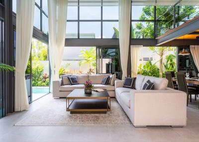 Modern living room with large windows, two sofas, a coffee table, and a view of the pool