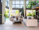 Modern living room with large windows, two sofas, a coffee table, and a view of the pool