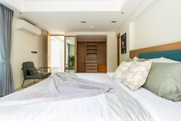 Modern bedroom with double bed, closet, and seating area