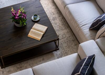 Top view of a modern living room with a coffee table, flowers, and an open book.