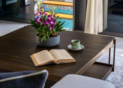 Modern living room with a coffee table, a potted plant, an open book, and a cup on a saucer