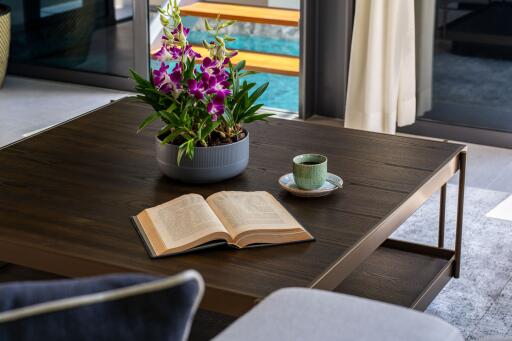 Modern living room with a coffee table, a potted plant, an open book, and a cup on a saucer