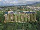 Aerial view of a modern residential building surrounded by lush greenery with a mountainous background