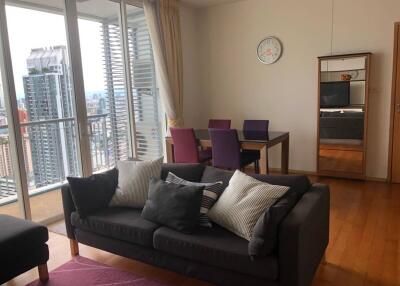 Modern living room with a sofa, dining table, and city view balcony