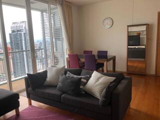 Modern living room with a sofa, dining table, and city view balcony