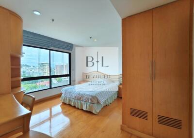 Spacious bedroom with wooden flooring and a large window allowing natural light.