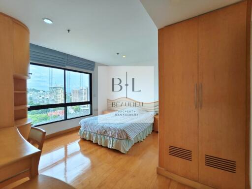 Spacious bedroom with wooden flooring and a large window allowing natural light.