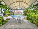 Covered outdoor seating area with building and pool in the background