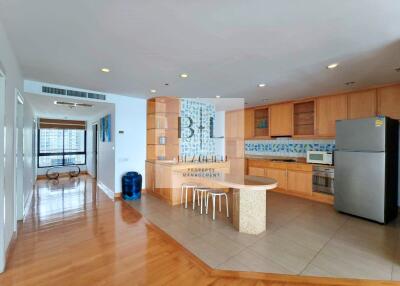 Modern kitchen with wood cabinetry and adjacent open area