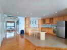 Modern kitchen with wood cabinetry and adjacent open area