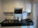 Modern kitchen with black countertop, sink, microwave, and induction cooktop