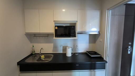 Modern kitchen with black countertop, sink, microwave, and induction cooktop