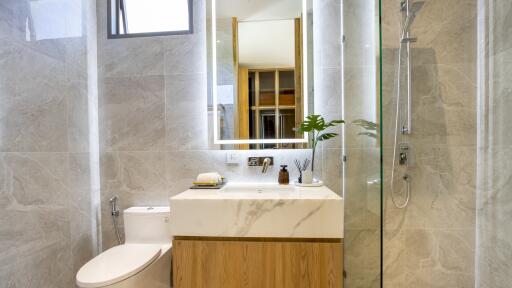 Modern bathroom with marble walls, shower, and sink