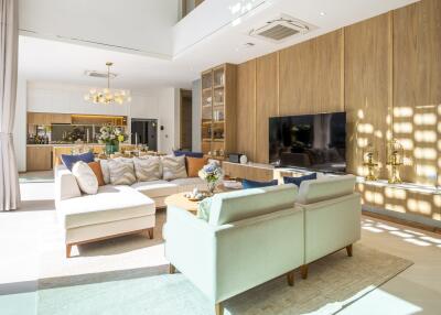 Modern living room with a sectional sofa, two chairs, and a large TV.