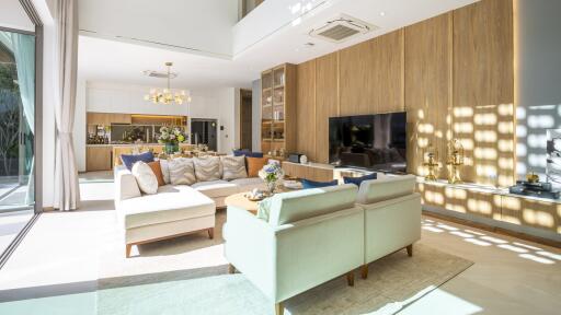 Modern living room with a sectional sofa, two chairs, and a large TV.