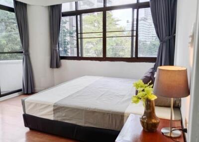 Bright bedroom with large windows and a view of trees