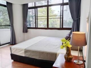 Bright bedroom with large windows and a view of trees