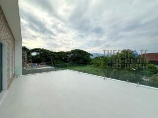 Spacious outdoor patio with glass railing and scenic view