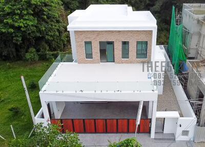 Modern two-story house with a large flat roof, red and white exterior, and a balcony.