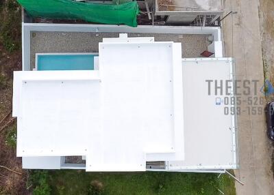 Aerial view of a modern building with a swimming pool and surrounding greenery