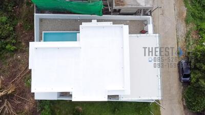 Aerial view of a modern building with a swimming pool and surrounding greenery