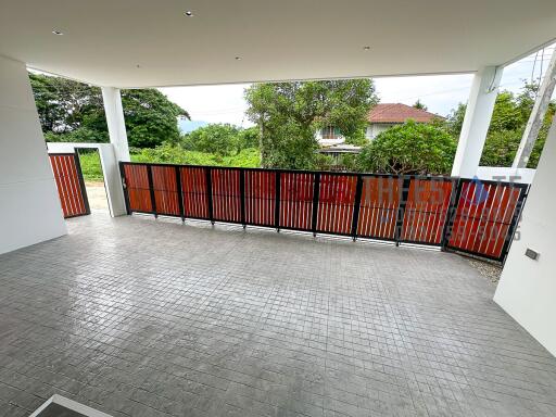 Spacious covered outdoor area with tiled flooring and a view of a well-maintained garden and neighborhood