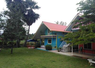 Colorful house with porch and surrounding greenery