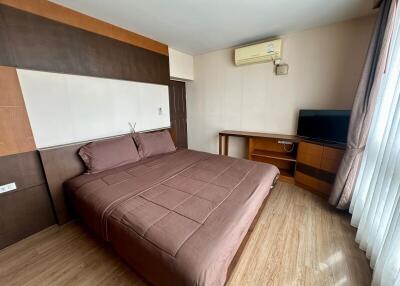 A modern bedroom with a double bed, wooden furniture, and a mounted air conditioning unit