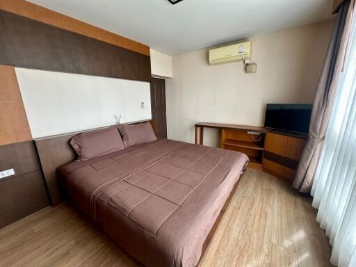 A modern bedroom with a double bed, wooden furniture, and a mounted air conditioning unit