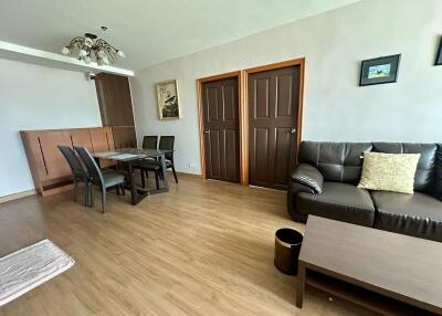 Modern living room with wooden flooring, dining area, and a leather sofa