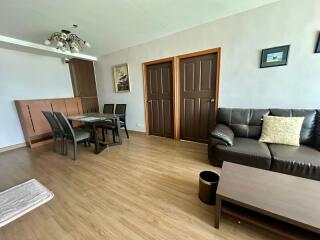 Modern living room with wooden flooring, dining area, and a leather sofa