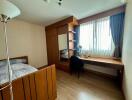 A well-lit bedroom with wooden furniture and a study desk by a window.