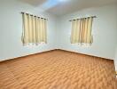 Empty bedroom with tiled floor and two windows with curtains