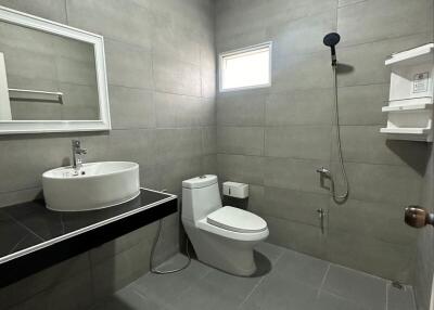 Modern bathroom with gray tiles, a white sink, and a shower