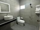 Modern bathroom with gray tiles, a white sink, and a shower