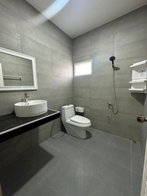 Modern bathroom with gray tiles, a white sink, and a shower