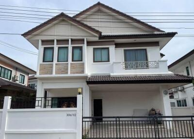 Exterior view of a two-story house with a white fence and tiled roof