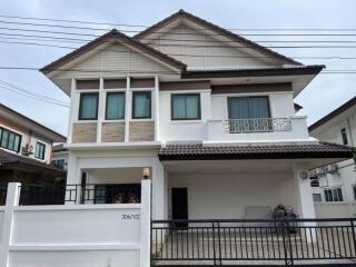 Exterior view of a two-story house with a white fence and tiled roof