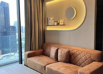 Modern living room with brown leather sofa and wall-mounted shelf, featuring city view from a high-rise building