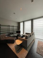 Modern living room with large windows, a couch, recliner, shelves, and a TV