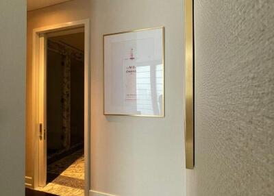 Interior view of a hallway with framed artwork and door leading to another room