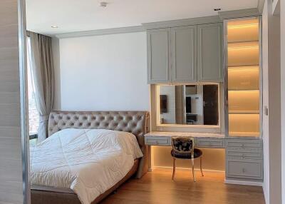 Modern bedroom with built-in wardrobe and vanity, wooden flooring, and large window