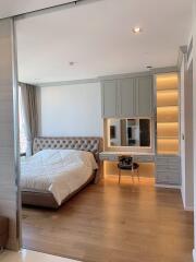 Modern bedroom with built-in wardrobe and vanity, wooden flooring, and large window