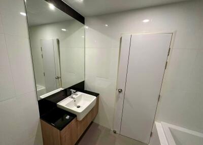 Modern bathroom with a large mirror, sink, and bathtub